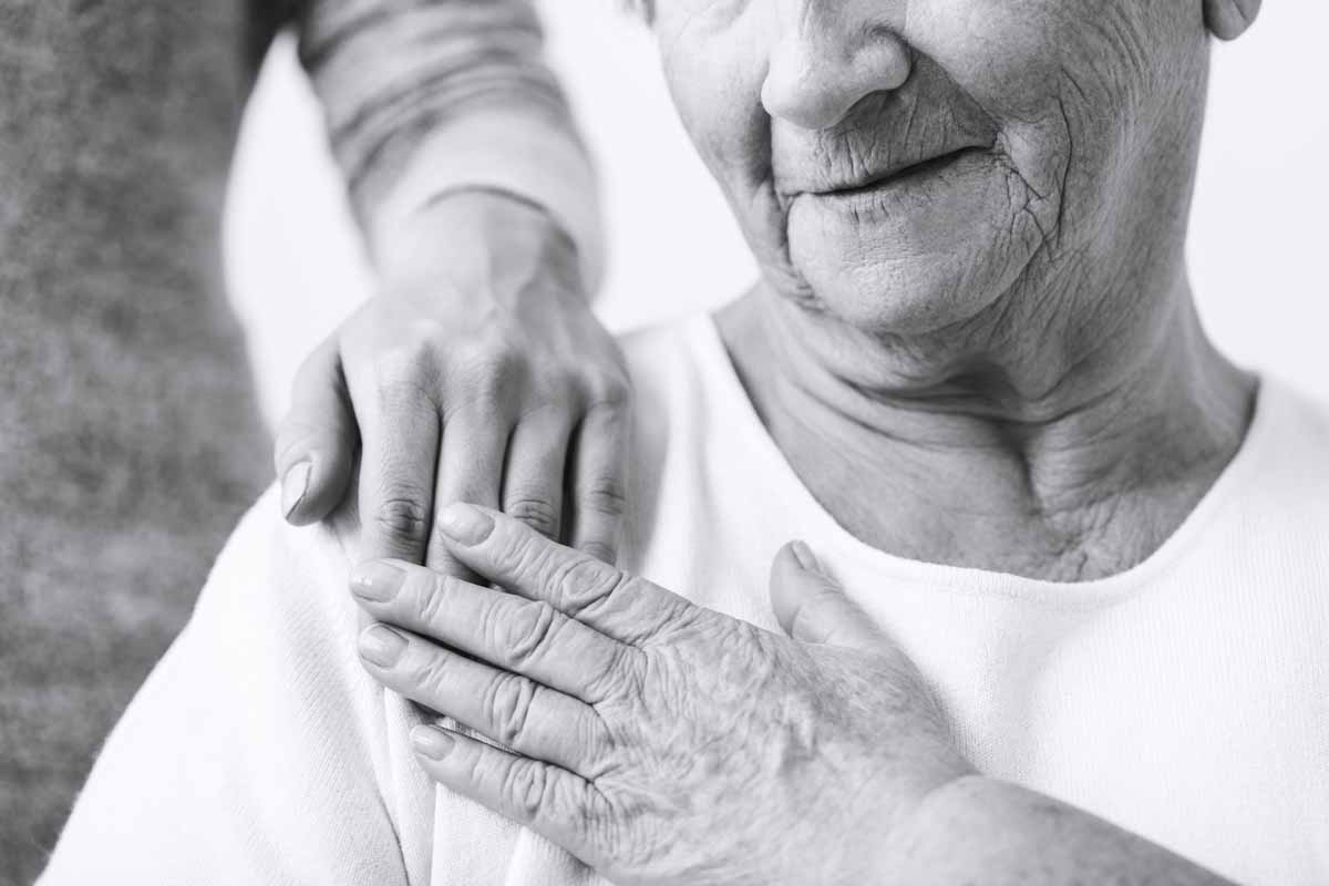 image of elderly women with the hand of a younger person on her shoulder