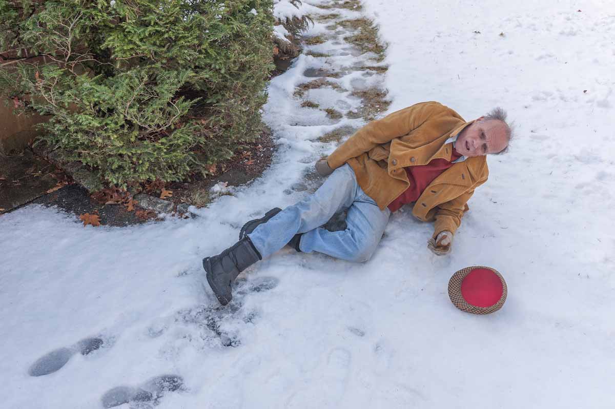 Elderly man who has fallen on snowy sidewalk