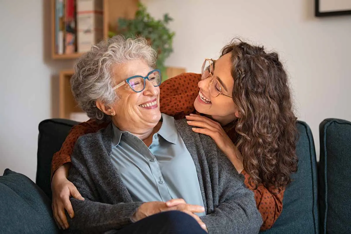 An adult daughter talking warmly with her mother on a couch
